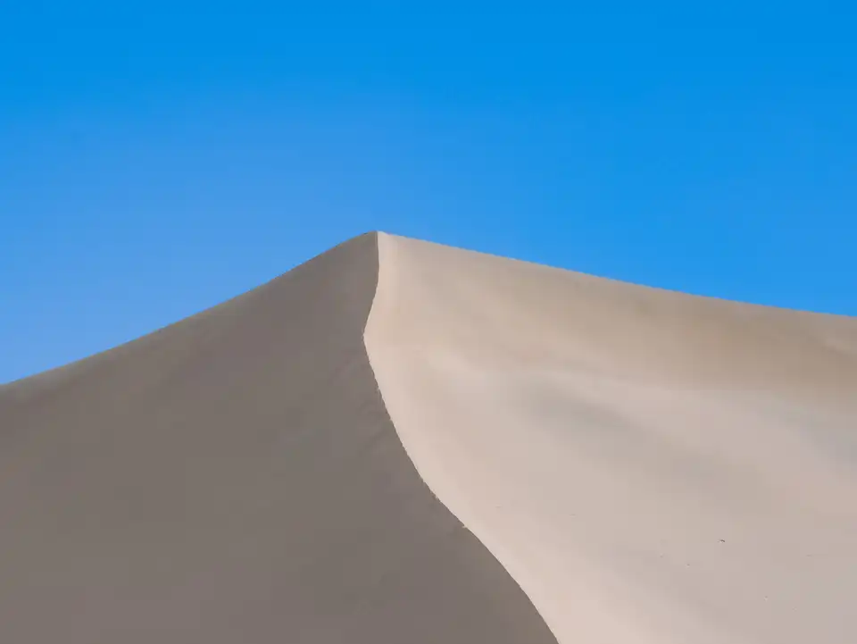 Curved sand dune ridge in Dunhuang with wind-shaped ripples in the sand.