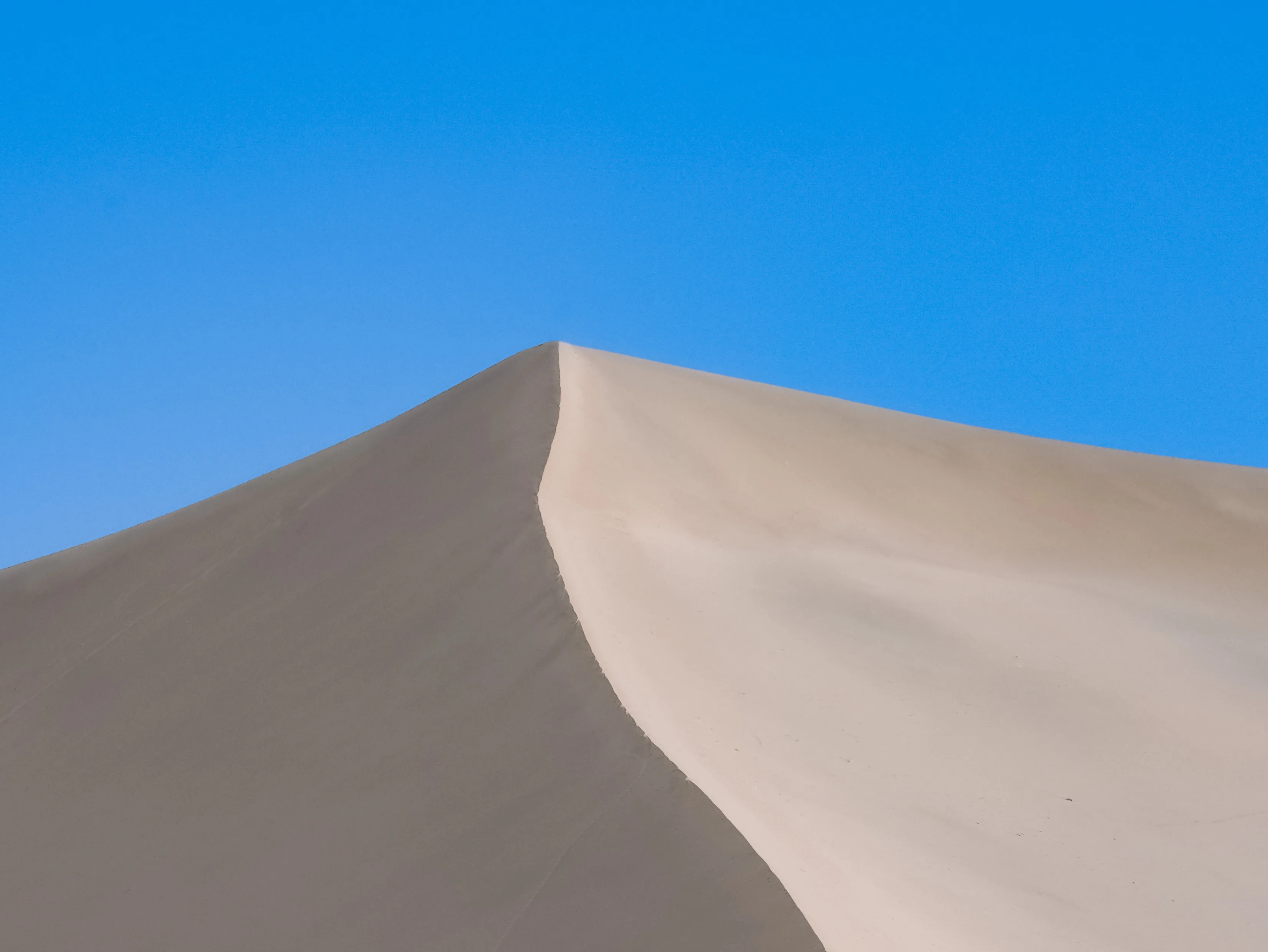 Curved sand dune ridge in Dunhuang with wind-shaped ripples in the sand.