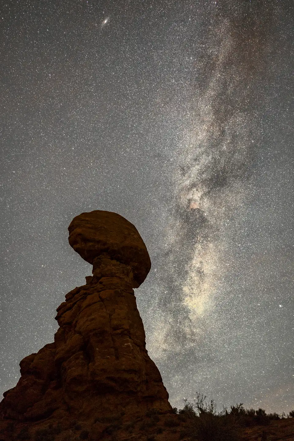 Milky Way above Balanced Rock in Arches National Park, with the rock formation below.